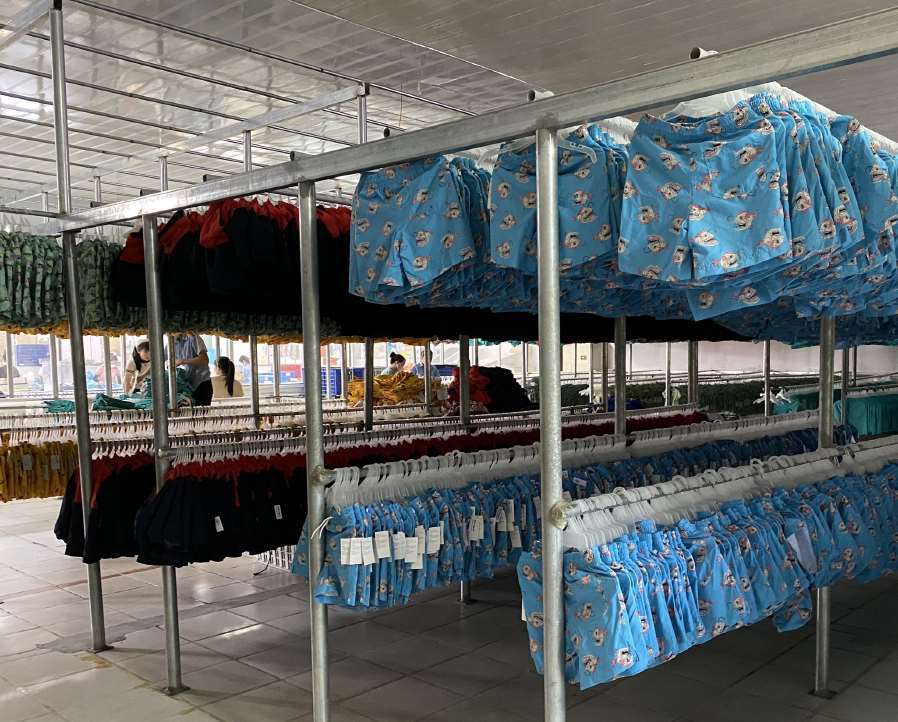Garments arranged on hanging racks in the Hanoi factory